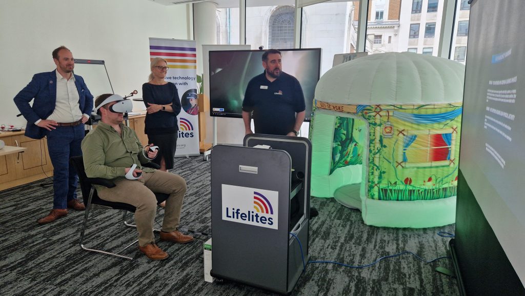 A group of people is looking at a man using the Lifelites VR headset